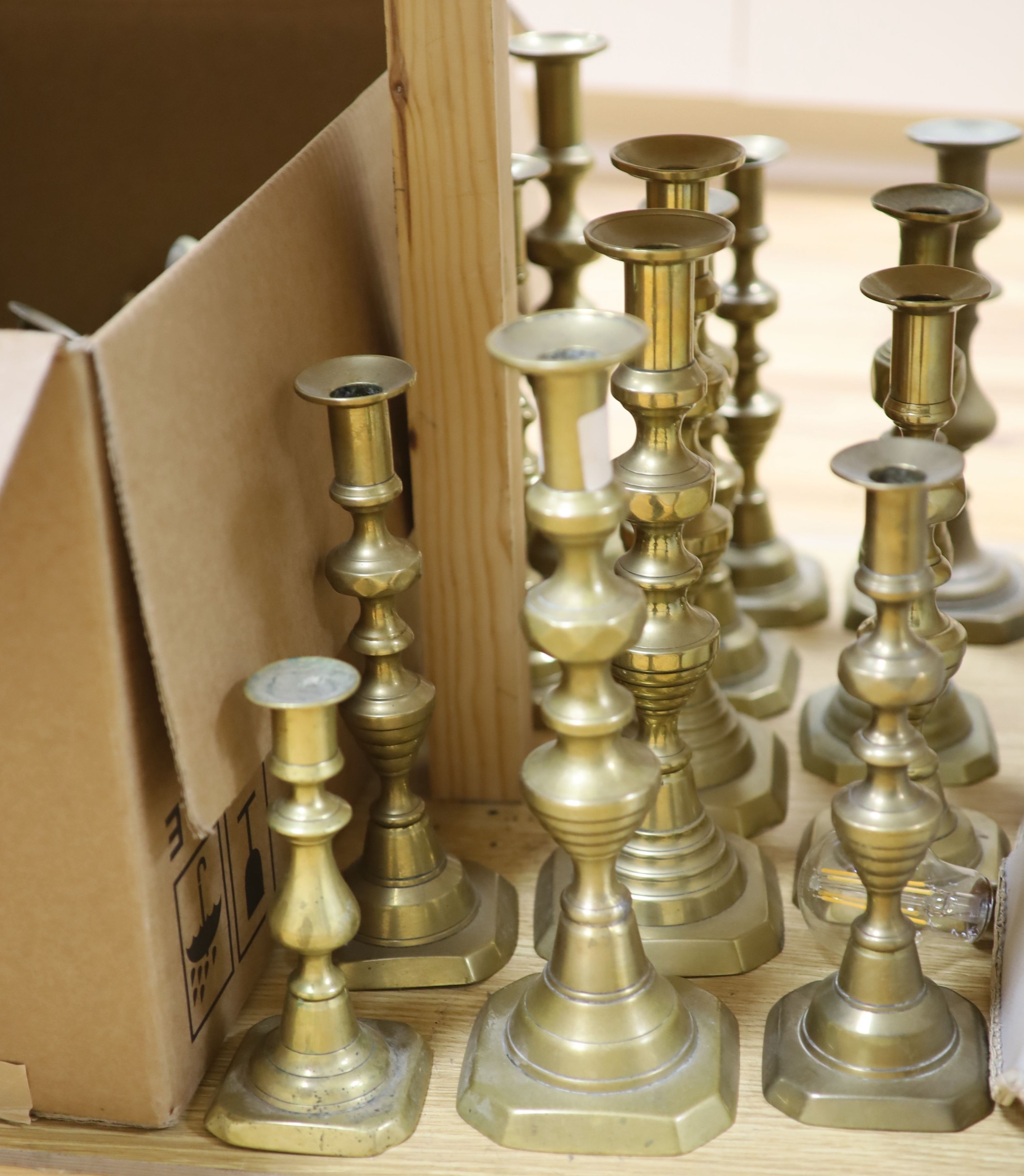 A collection of nineteen pairs of brass candlesticks and three odd